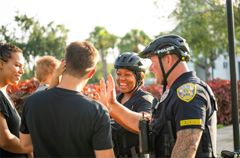 Bike-Unit-officers-high-fiving-family-at-the-park.png